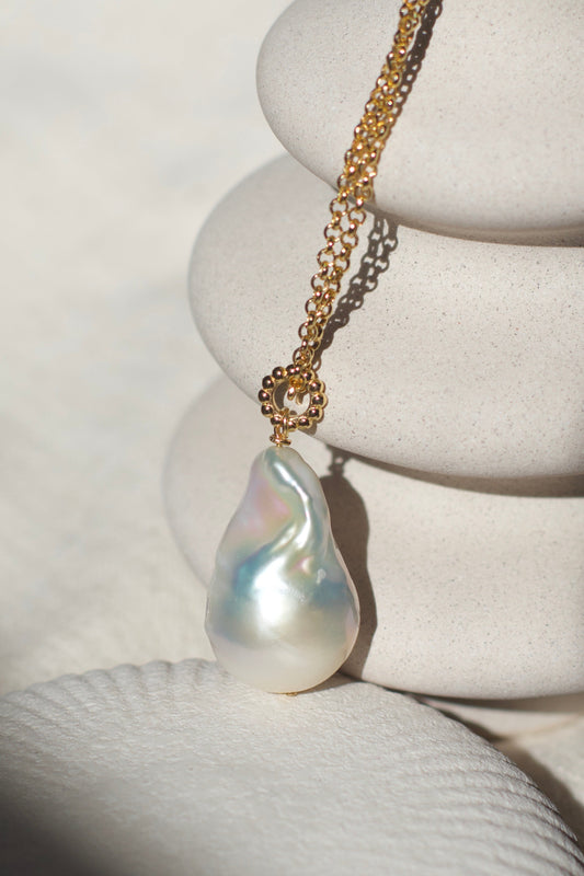 Pearl necklace on a white stone surface with a shell