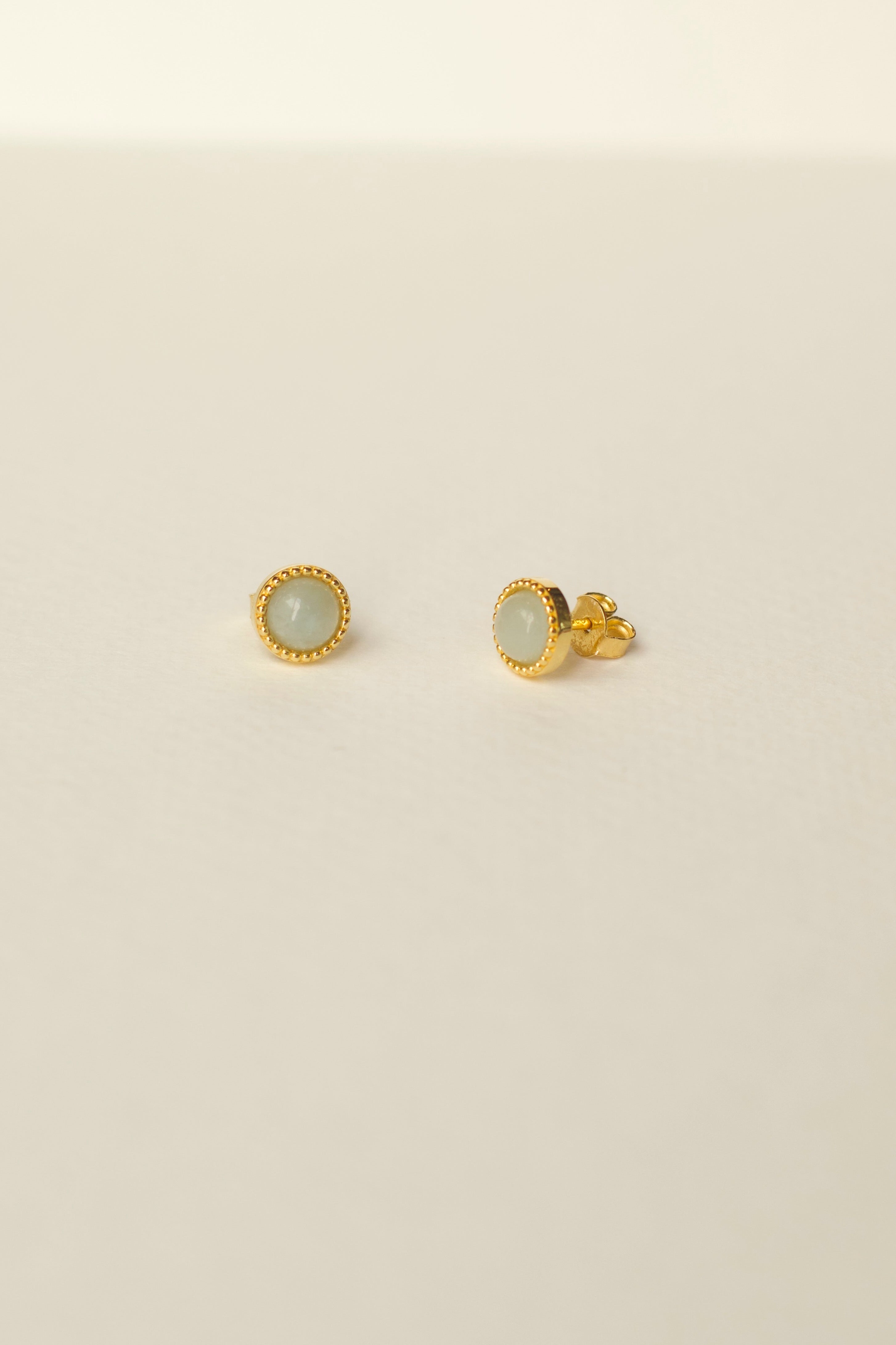 Pair of gold aquamarine earrings on a beige background