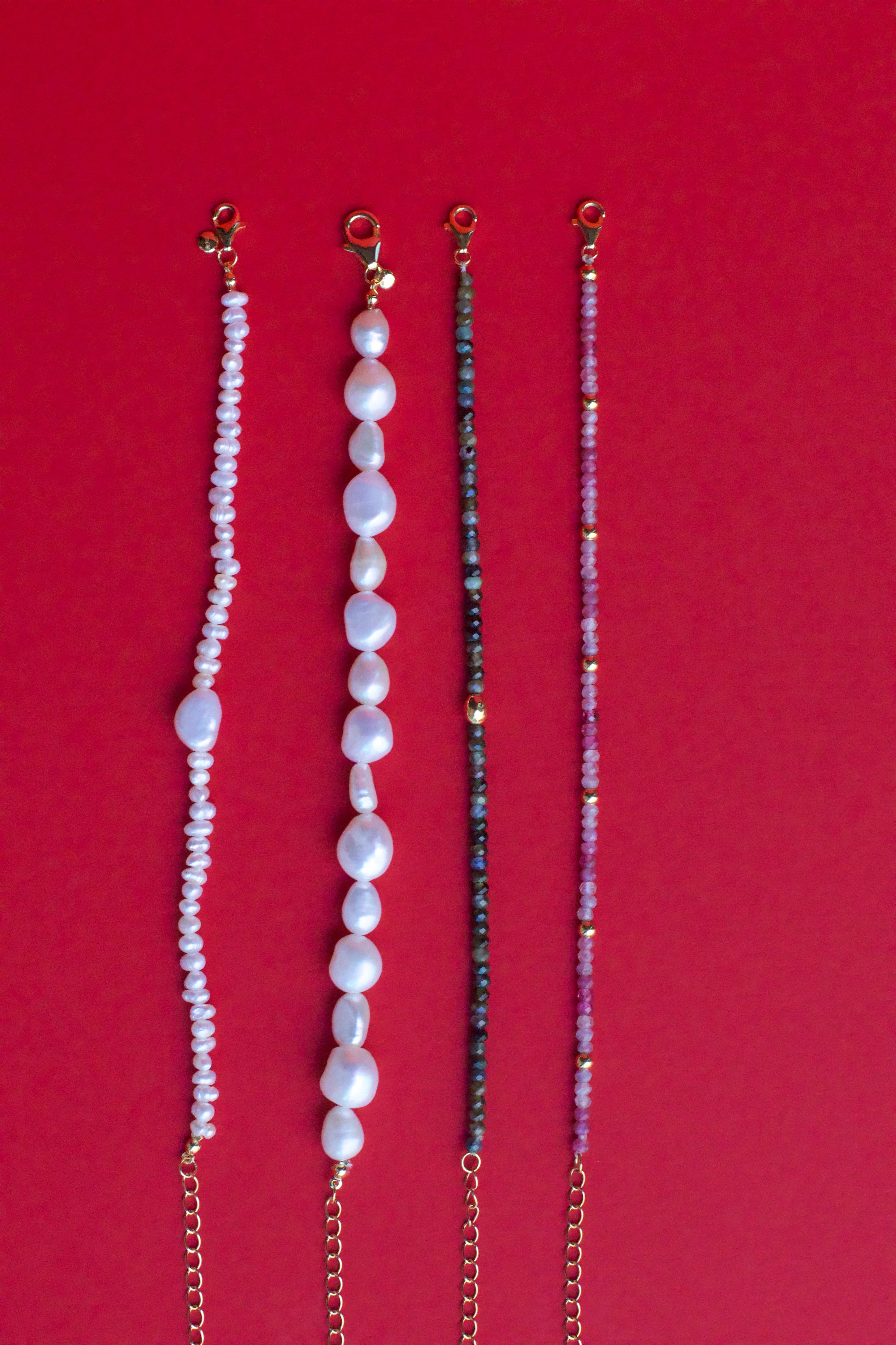 Tourmaline and pearl bracelets on red background