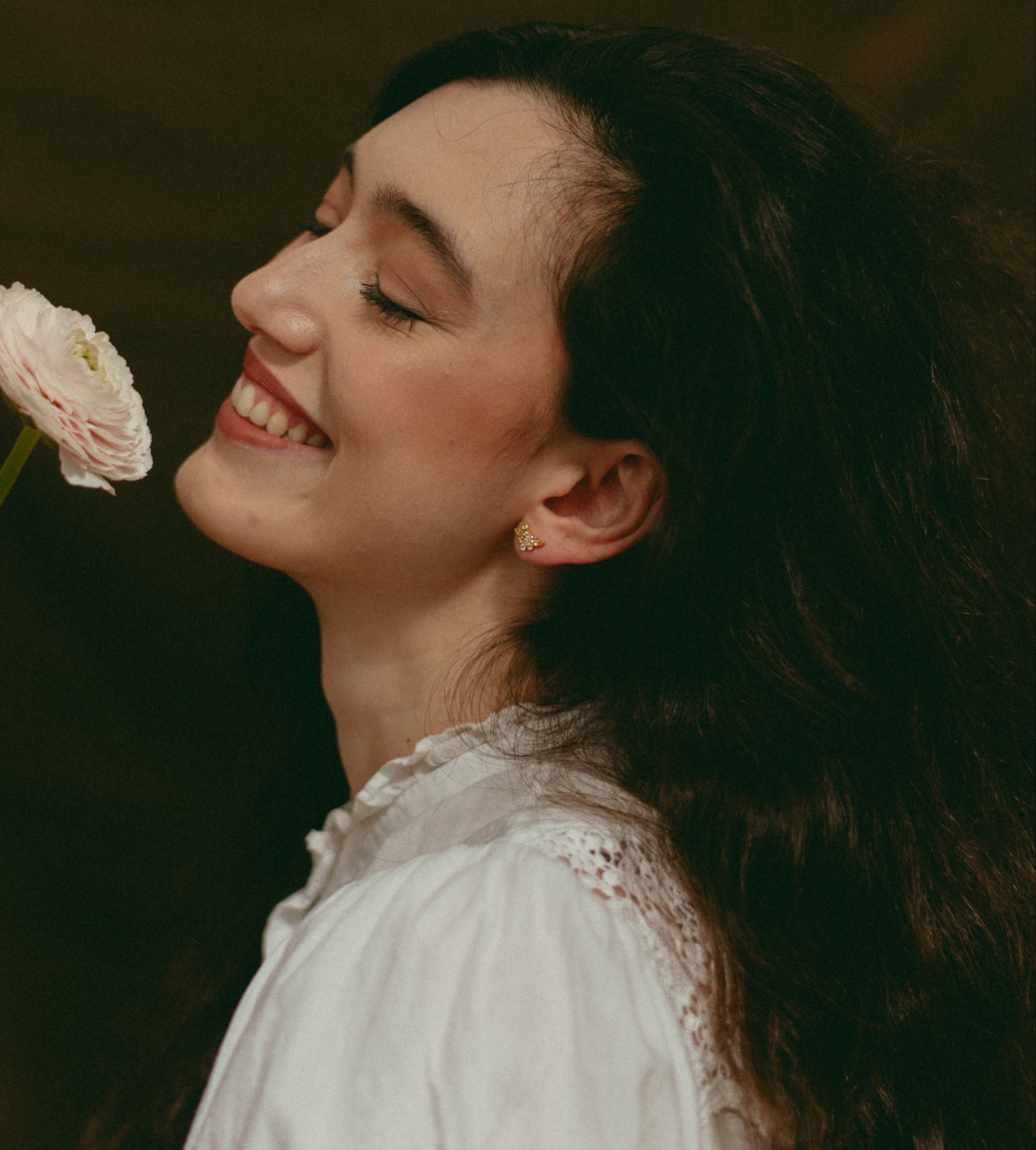 Woman holding a flower against a dark background
